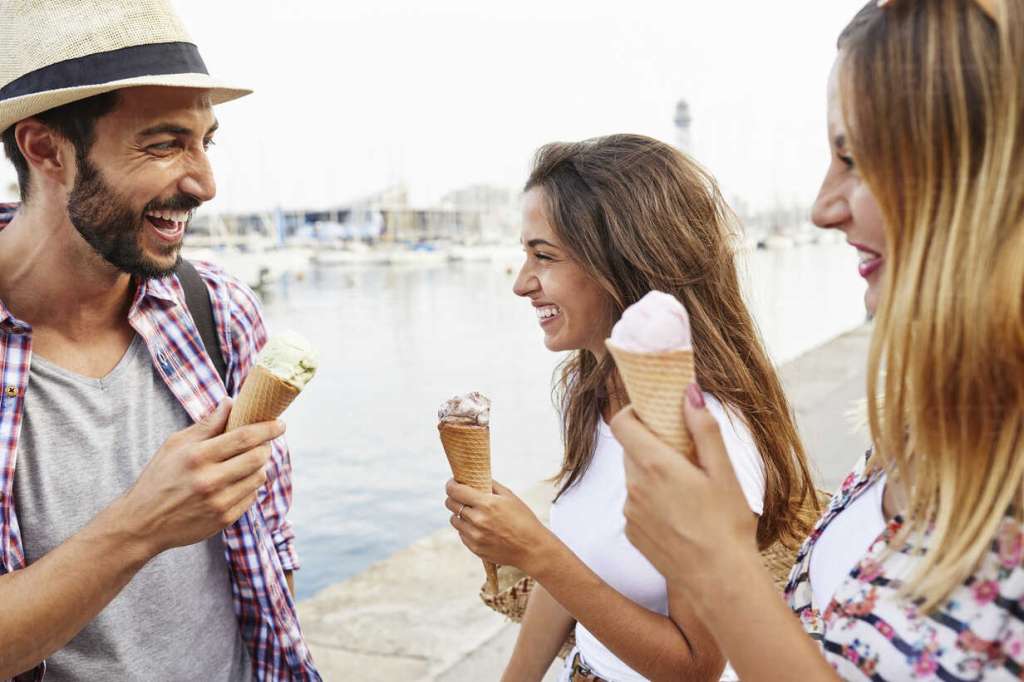 Spain, Barcelona. Three friends eating an ice cream in the center of the city